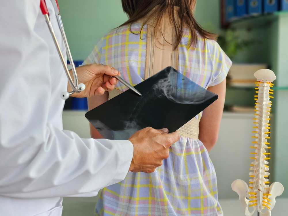 Doctor,examines,an,x Ray,of,a,patient,wearing,a,back