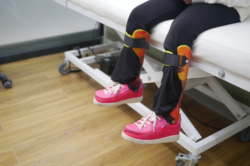 Child's,legs,with,orthopedic,braces,and,bright,pink,shoes,on